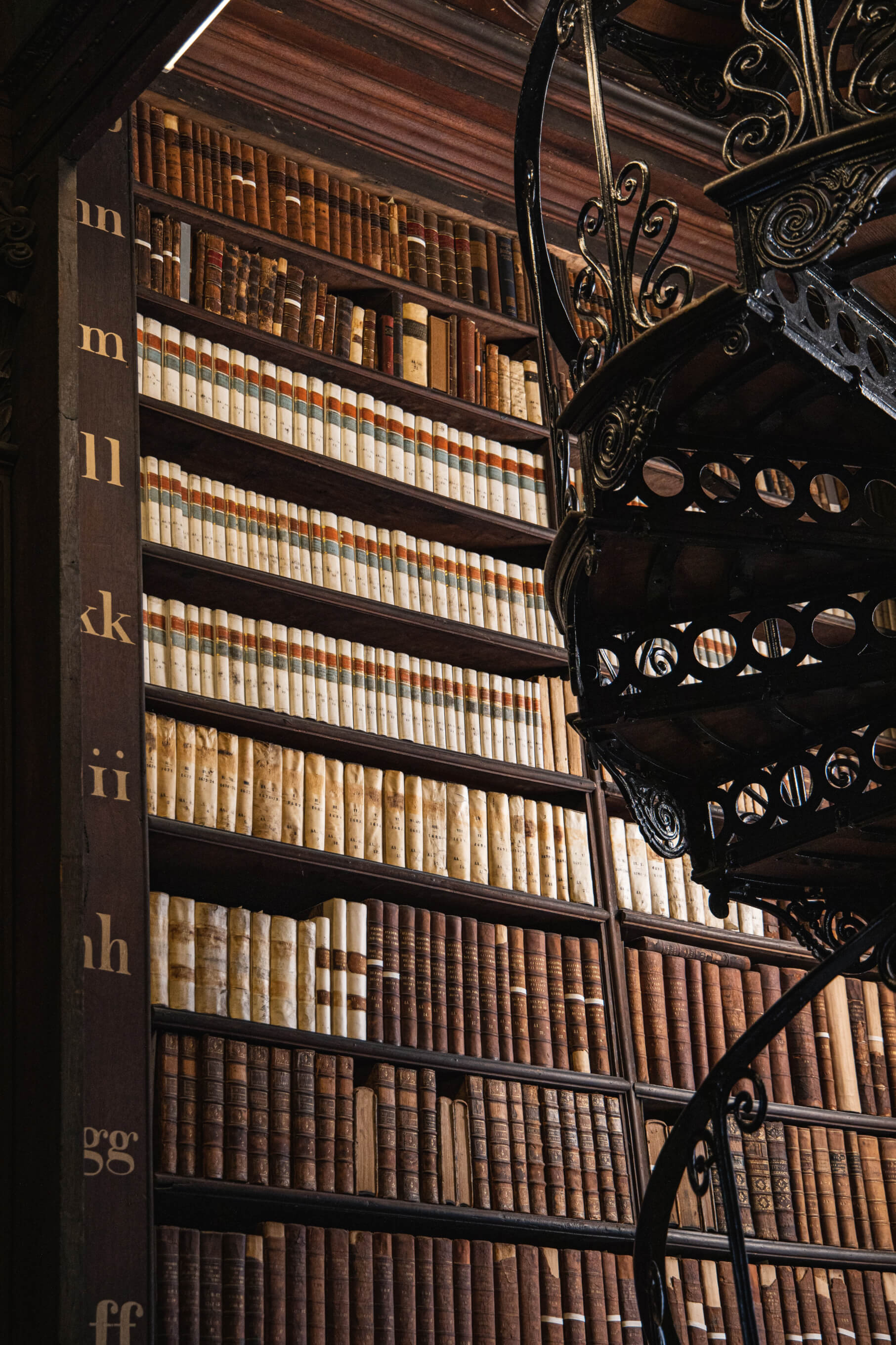 books on a library wall with a spiral staircase